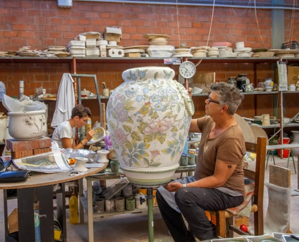 Artisan decorating a large ceramic vase during the Montelupo factory tour