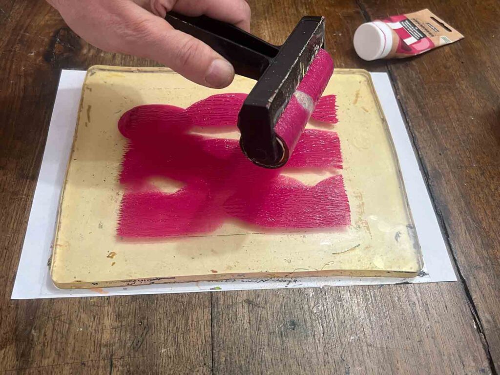 Rolling magenta acrylic color onto a gel plate at a gel plate printing Florence workshop for kids at Fatacadabra