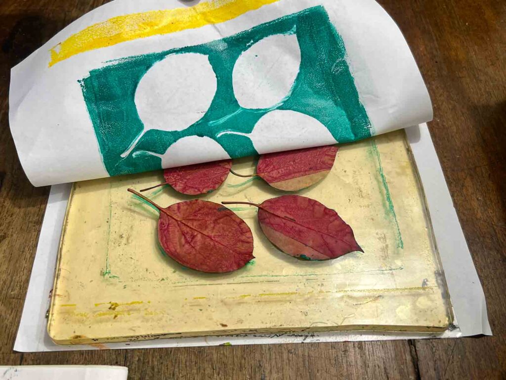 Peeling back paper to reveal a teal leaf monoprint at a kids art workshop Tuscany, Fatacadabra