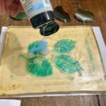 Pouring white medium over leaf impressions on the gel plate in a family art class Tuscany