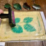Rolling teal acrylic over leaf impressions on the gel plate at a gel plate printing Florence session