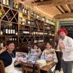 Students holding certificates with chef in wine cellar kitchen