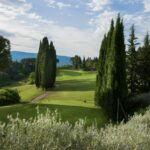 Green fairway lined with cypress trees at a golf course in Chianti.