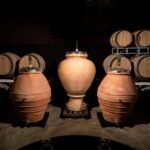 Terracotta amphorae and oak barrels inside a Chianti winery cellar.