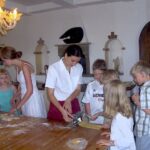 Children and adults making fresh pasta together during a family friendly Tuscan cooking in a farmhouse.