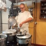 Chef stirring a pot at the stove during a private cooking in Florence.
