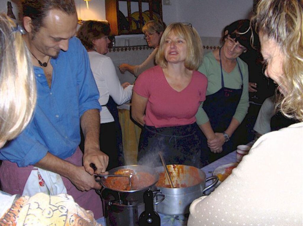 Chef preparing tomato sauce while guests watch during a hands-on cooking class in Florence.