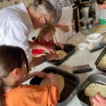 Children shaping dough with chef guidance during a family-friendly cooking in Florence.