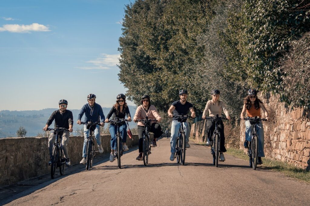 Small group riding e-bikes through the Florentine hills surrounded by olive trees