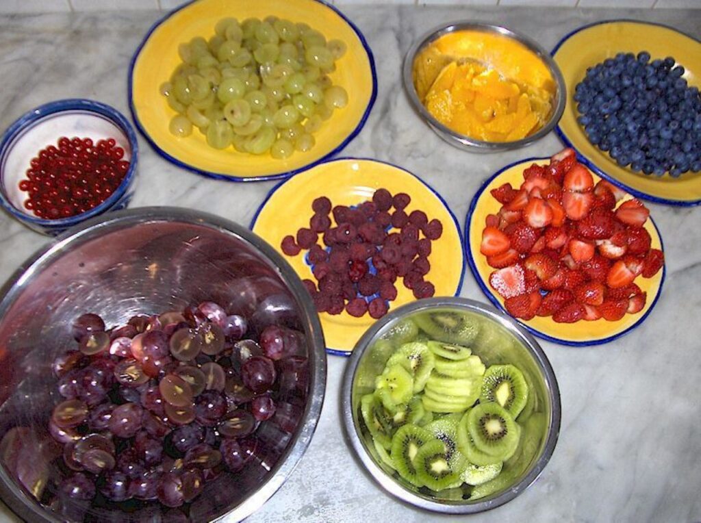 Bowls of fresh grapes, berries, kiwi, and citrus prepared in a Tuscan farmhouse kitchen.