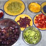 Bowls of fresh grapes, berries, kiwi, and citrus prepared in a Tuscan farmhouse kitchen.