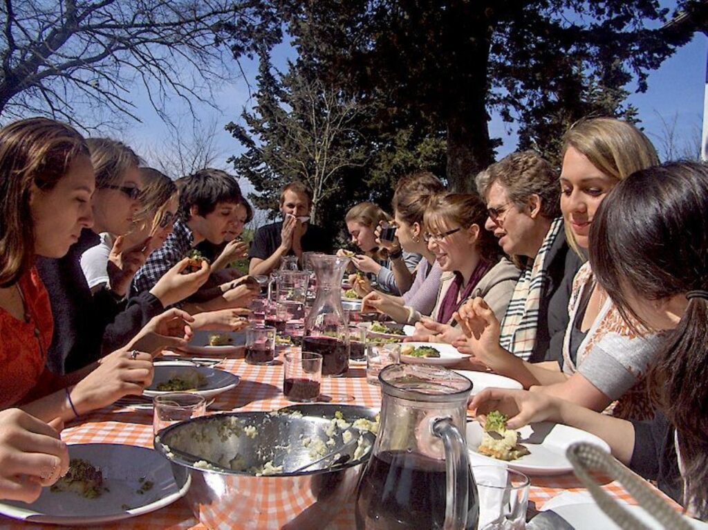 Group of guests dining together outdoors after a private Tuscan farmhouse cooking class.