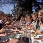 Group of guests dining together outdoors after a private Tuscan farmhouse cooking class.