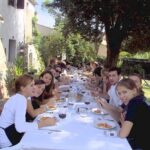 Guests enjoying an outdoor meal in the farmhouse garden after a Tuscan countryside cooking class.