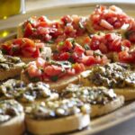 Plate of bruschetta topped with fresh tomato and savory spreads in a Tuscan cooking class.