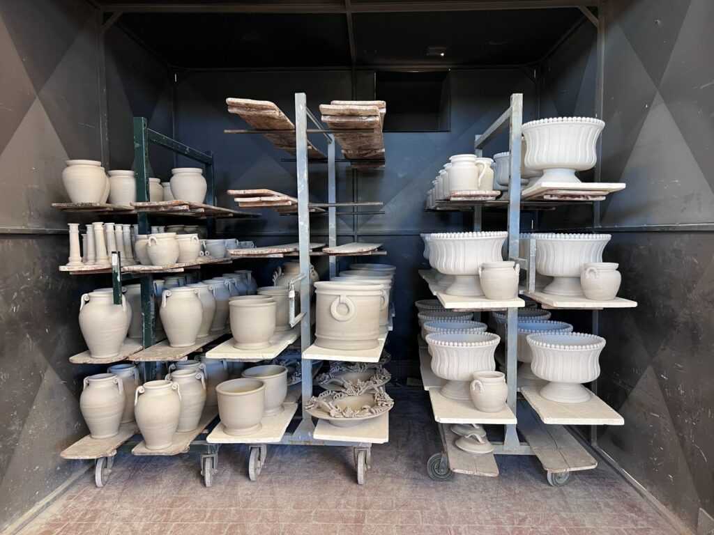 Unfired ceramic pieces drying on racks after production in the factory