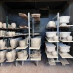 Unfired ceramic pieces drying on racks after production in the factory