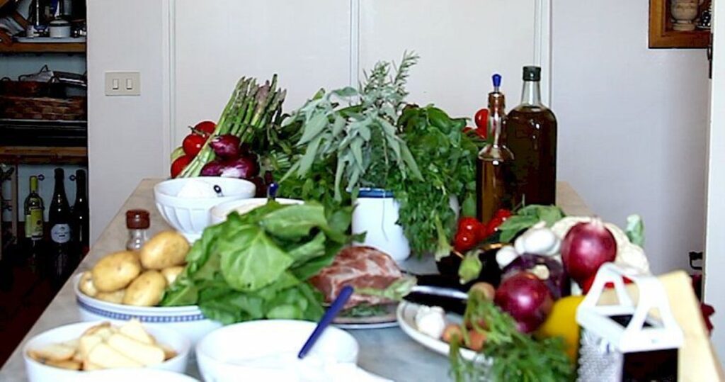Fresh vegetables, herbs, olive oil, and local products prepared for a Tuscan countryside cooking class.