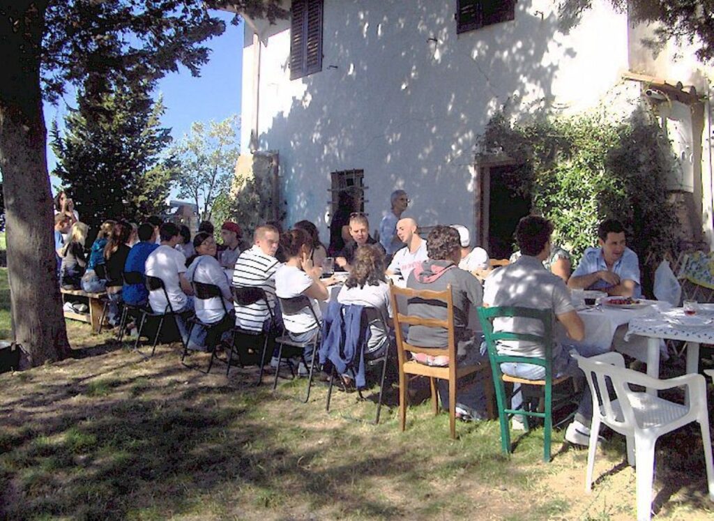 Large group dining in the farmhouse garden during a Tuscan countryside cooking class experience.