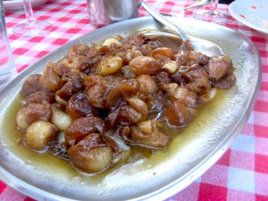 Traditional Tuscan meat dish served with onions during a countryside farmhouse cooking class meal.