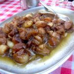 Traditional Tuscan meat dish served with onions during a countryside farmhouse cooking class meal.