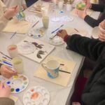 Small group of participants painting ceramic mugs and plates during a ceramic painting in Florence