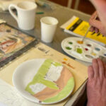 Participant painting a ceramic plate with a Tuscan landscape design during a ceramic painting in Florence