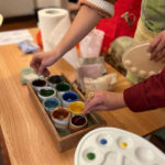 Art teacher and student selecting Maiolica colors during a ceramic painting in Florence