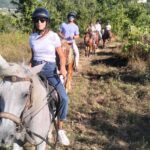 Group riding single file through a vineyard trail on the Chianti horseback lunch tour from Florence