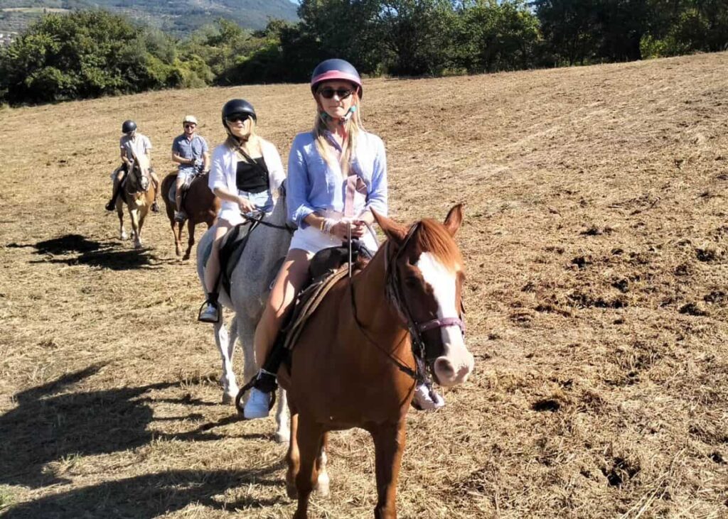 Group of riders crossing an open field on the Chianti horseback lunch tour from Florence in Pelago