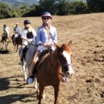 Group of riders crossing an open field on the Chianti horseback lunch tour from Florence in Pelago