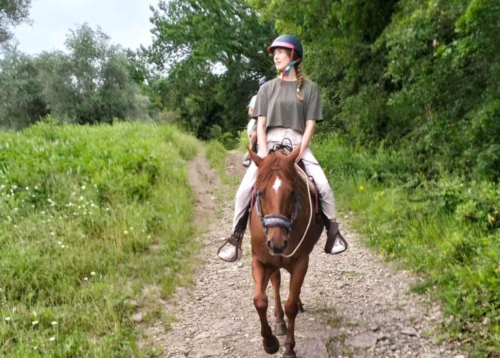 Rider on horseback along a green country trail on the private Chianti horseback ride from Florence