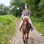 Rider on horseback along a green country trail on the private Chianti horseback ride from Florence