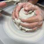 Hands centering clay during the ceramics wheel workshop near Florence