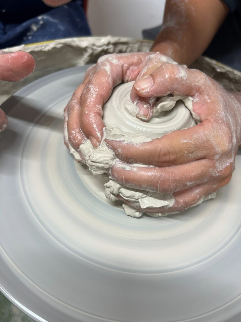 Hands centering clay during the ceramics wheel workshop near Florence