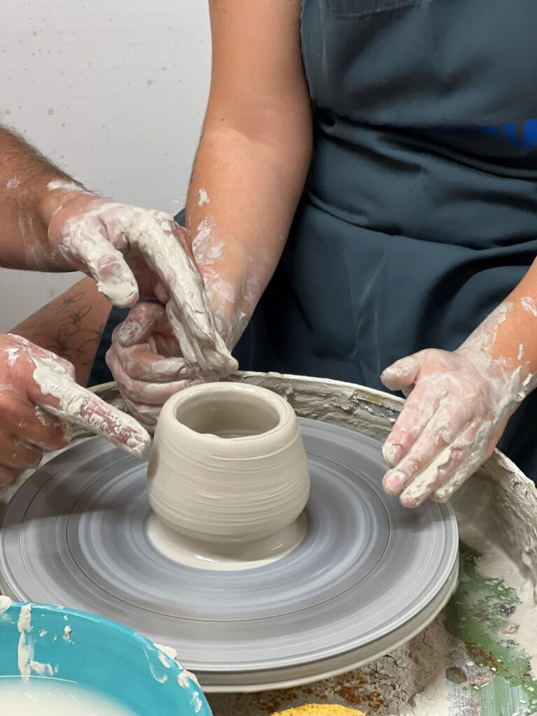Shaping a vessel on the wheel during an intermediate pottery workshop Italy