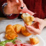 Hands tasting fried dough and prosciutto during a market food tour Florence with kids