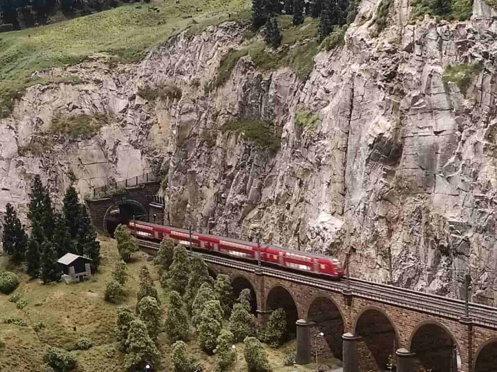 Miniature red train crossing a mountain viaduct at HZERO Museum Florence with kids