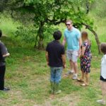 Small private group with a local producer in a Chianti garden during a wine tasting near florence, with olive trees and open countryside surrounding them.