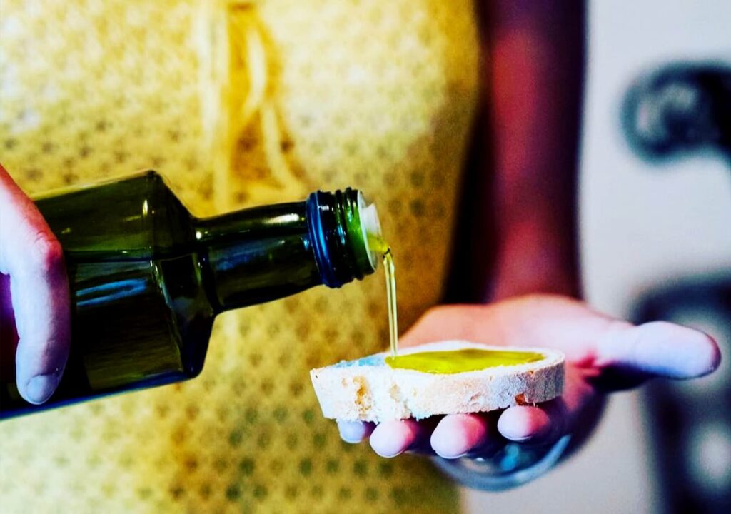 Extra virgin olive oil poured on Tuscan bread during an olive oil tasting tuscany experience included in a private wine tour from Florence.